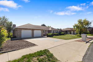 Single story home featuring a garage, driveway, brick siding, roof with shingles, and a chimney