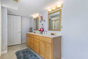 Full bath featuring double vanity, a shower stall, and light tile patterned flooring