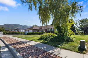 Single story home featuring a front yard, a mountain view, stone siding, and an attached garage