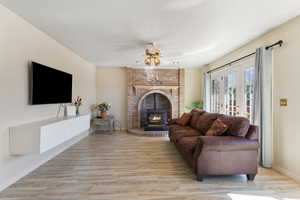 Living area with a wood stove, light wood finished floors, and ceiling fan