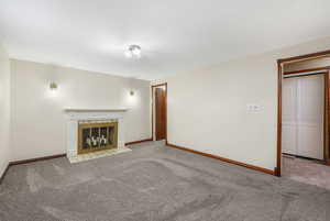 Unfurnished living room with carpet and a tiled fireplace