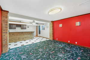Unfurnished living room with bar with sink and a ceiling fan