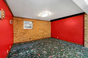 Additional living space with brick wall and a textured ceiling