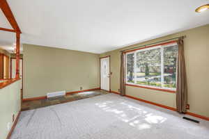 Carpeted empty room featuring baseboards and stone finish flooring