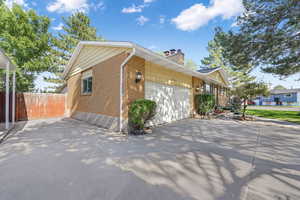 View of home's exterior with brick siding, a chimney, driveway, and an attached garage