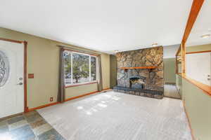 Unfurnished living room with a stone fireplace, carpet, and stone finish floors