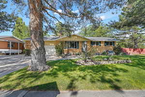 Single story home featuring brick siding, an attached garage, driveway, and a chimney