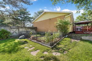 View of home's exterior featuring a deck, a garden, brick siding, a gate, and a gazebo