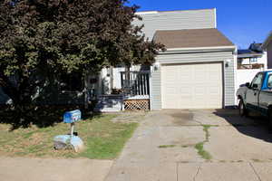 View of front of house featuring concrete driveway, a shingled roof, a garage, and a wooden deck