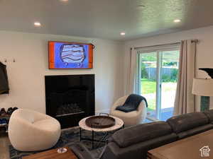 Living room featuring wood finished floors, a fireplace, recessed lighting, and a textured ceiling