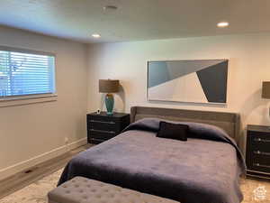 Bedroom with light wood-style floors, recessed lighting, and a textured ceiling