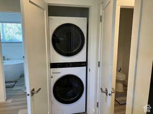Washroom with wood finished floors and stacked washer / dryer