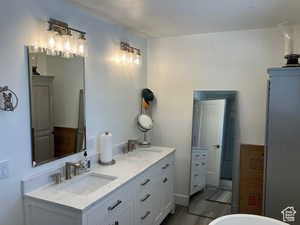 Bathroom featuring double vanity, light wood-style floors, and a soaking tub