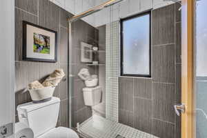 Bathroom featuring a shower stall and tile walls