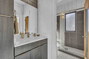 Full bath featuring a shower stall, vanity, tile patterned flooring, and healthy amount of natural light