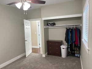 Carpeted bedroom with a closet and ceiling fan