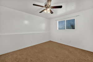 Carpeted empty room featuring baseboards and ceiling fan