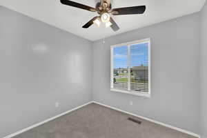 Carpeted spare room featuring baseboards and ceiling fan