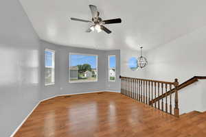 Unfurnished room with wood finished floors, a chandelier, and ceiling fan