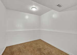 Carpeted spare room featuring a textured ceiling and baseboards