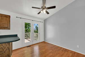 Entryway with wood finished floors, a ceiling fan, and lofted ceiling