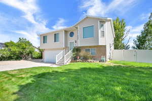Split foyer home featuring concrete driveway, a garage, a gate, and brick siding