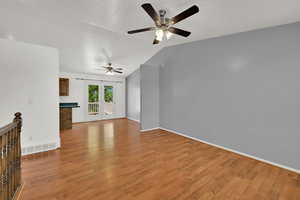 Unfurnished living room with lofted ceiling, light wood-type flooring, and ceiling fan