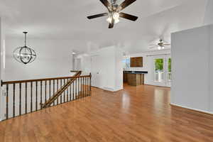 Unfurnished living room featuring lofted ceiling, light wood finished floors, and a chandelier