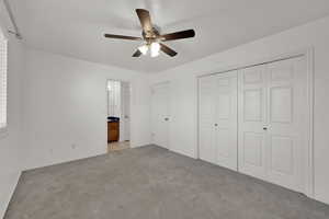 Unfurnished bedroom with light colored carpet, ceiling fan, and a closet