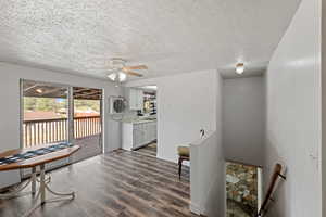 Sitting room with dark wood finished floors, a ceiling fan, a textured ceiling, and an upstairs landing