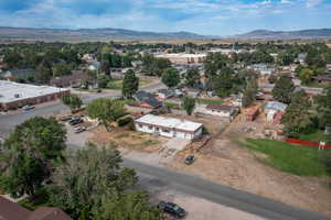 Aerial view of property and surrounding area featuring a mountain backdrop and nearby suburban area