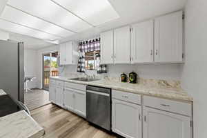 Kitchen with white cabinets, appliances with stainless steel finishes, light wood finished floors, and light countertops
