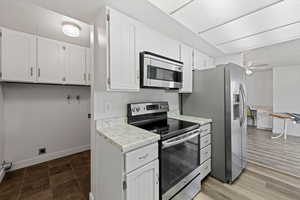 Kitchen with stainless steel appliances, white cabinets, light countertops, and ceiling fan