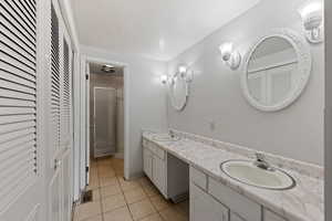 Bathroom with a closet, double vanity, light tile patterned floors, and a shower stall