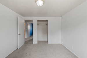 Unfurnished bedroom with light carpet and a closet