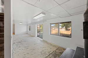 Empty room with stairs, healthy amount of natural light, and a drop ceiling