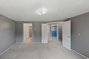 Unfurnished bedroom featuring light carpet and a textured ceiling