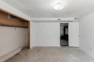 Unfurnished bedroom featuring unfinished concrete floors and a closet