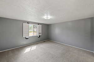 Empty room featuring carpet and a textured ceiling