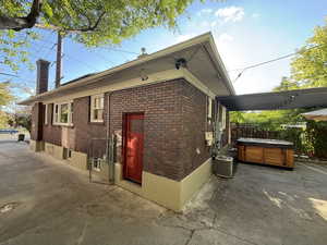 View of side of home featuring brick siding, a hot tub, and a chimney