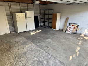 Garage featuring freestanding refrigerator and a garage door opener