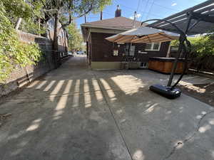 Rear view of property with a hot tub, brick siding, a chimney, and roof with shingles