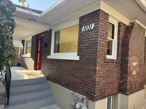 View of side of home featuring brick siding and covered porch