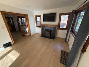 Unfurnished living room featuring light wood-style floors and a high end fireplace