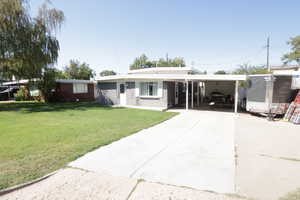 View of front of house featuring driveway, an attached carport, a front yard, and brick siding