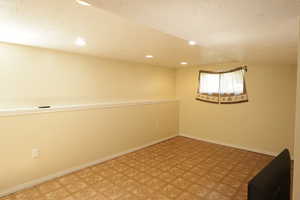 Below grade area featuring a textured ceiling, recessed lighting, and light flooring