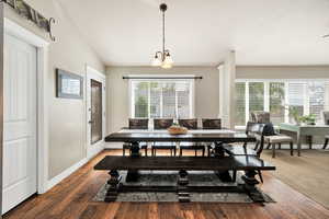 Dining space with wood-type flooring, a chandelier, lofted ceiling, and a textured ceiling