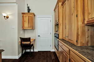 Kitchen with dark wood-style flooring, black oven, and cabinetry