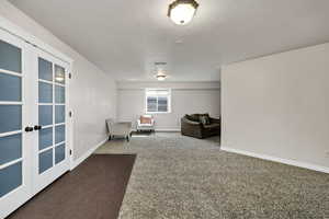 Living area featuring dark colored carpet and a textured ceiling