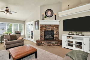 Living area with light carpet, a fireplace, high vaulted ceiling, and a ceiling fan